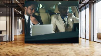 two business partners working together in front seat of car at evening dark time Wall mural