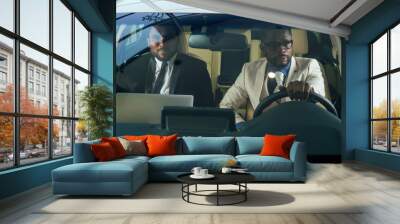 two business partners working together in front seat of car at evening dark time Wall mural