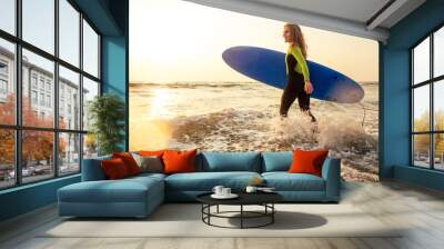 Young freelancing woman in a wetsuit swimming over surfboard in the water at beach.surfer girl relaxing in paradise island sunset romance and freelance freedom in the Indian Ocean. Wall mural