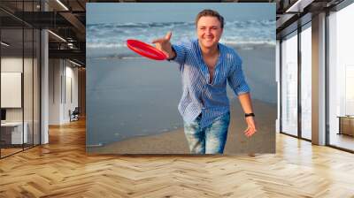 young man playing flying disk on the beach in the morning Wall mural