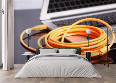 laptop with orange rolled cable Wall mural