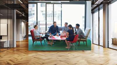 An assemblage of sharp minds. a group of office workers talking together in a meeting room. Wall mural