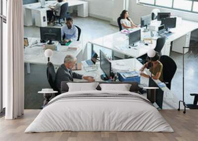 Everyones focused on their tasks. Shot of a group of coworkers sitting at their workstations in an office. Wall mural