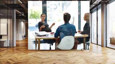 Shes the parent of this company. Shot of a pregnant businesswoman having a meeting with colleagues in office. Wall mural