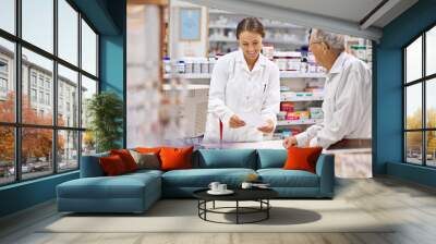 Everyone of my clients are special. Shot of a young pharmacist helping an elderly customer at the prescription counter. Wall mural