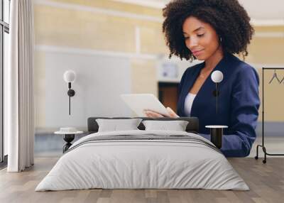 Going through my emails. Cropped shot of an attractive young businesswoman standing alone and using a tablet while in the office during the day. Wall mural