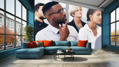 Hmm, so much to think about. Cropped shot of a handsome young businessman sitting with his colleagues while in the office during the day. Wall mural