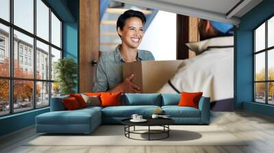 It got here so fast. Shot of a smiling young woman standing at her front door receiving a package from a courier. Wall mural