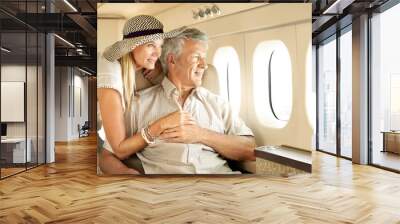 Taking a luxury trip. Smiling senior couple on an airplane looking out the window. Wall mural