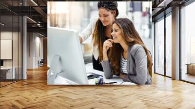 That looks good. Cropped shot of two attractive young businesswomen working at a desk in their office. Wall mural