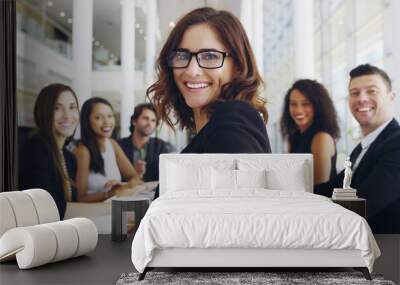 Young businesswoman smiling in an office during a meeting with her colleagues in the background. Wall mural