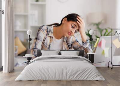 A tired young Indian girl gets angry from the number of tasks, crumples up the paper and throws it away, tries to calm down by meditating. Stressful work and study, overtasking, headache. Wall mural