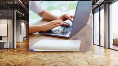 Beautiful Latin young woman in casual clothing using laptop and smiling while working indoors. lady work ny computer listening music with earphones. typing on the keyboard, close up Wall mural