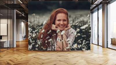 Beautiful young girl with curly red hair in chamomile field Wall mural