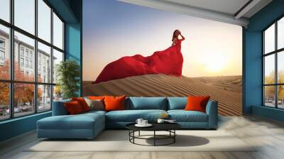 Desert adventure. Young arabian Woman in red silk dress in sands dunes of UAE desert at sunset, fantastic view. The Dubai Desert Conservation Reserve, United Arab Emirates. Wall mural