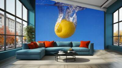 Whole lemon dropped in water against gradient blue background Wall mural