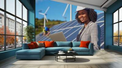 Engineer working on a project involving solar panels and wind turbines, focusing on renewable energy. This female professional is outdoors using a tablet, optimizing green technology Wall mural