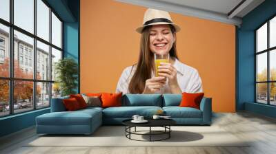 Happy emotional woman with eyes closed holding orange juice drink in glass. Isolated female advertising portrait. Wall mural