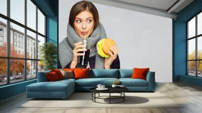 Portrait of woman wearing warm scarf eating fast food. Wall mural