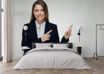 Smiling businesswoman wearing black suit pointing finger up at c Wall mural