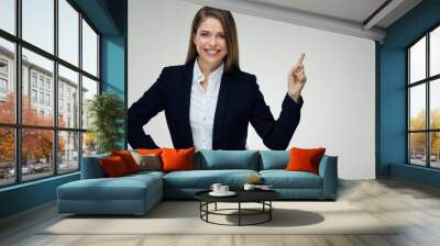 Smiling businesswoman wearing black suit pointing finger up at c Wall mural