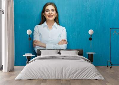 Smiling young business woman against blue wall. Wall mural