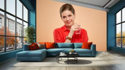 Smiling young lady in red shirt holding water glass isolated portrait. Wall mural