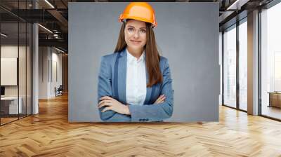 Woman builder engineer standing against gray wall with crossed arms. Wall mural