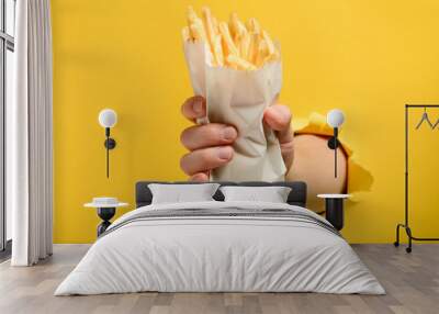 Hand holding French fries Wall mural