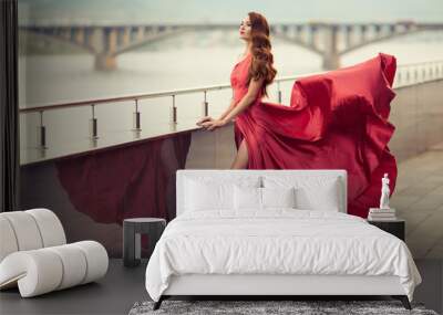 Beautiful woman in red fluttering dress. Urban background. Wall mural