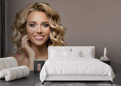 Blonde woman with curly beautiful hair smiling on gray background. Wall mural