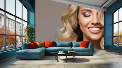 Blonde woman with curly beautiful hair smiling on gray background. Wall mural