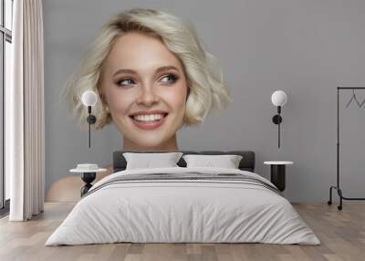 Portrait of a beautiful smiling blonde girl with a short haircut. Gray background. Wall mural