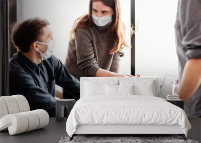 employees in protective masks discussing online information Wall mural