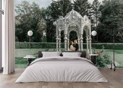 happy bride and groom standing in arched gazebo Wall mural