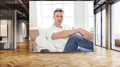 happy man sitting on the couch in his new apartment Wall mural