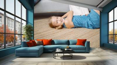 little girl is playing lying on the floor in the living room . Wall mural