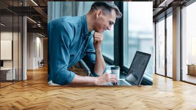 man with a laptop standing near the window . Wall mural