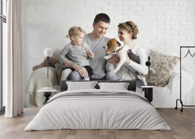 parents with a young daughter and pet sitting on the couch. Wall mural