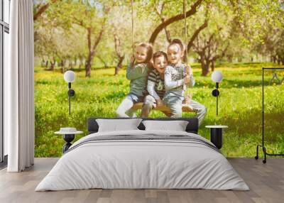 Three small children ride on the swings in the Park Wall mural