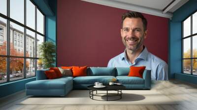 Cheerful man with warm smile posing against maroon background with copy space Wall mural