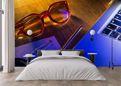 Notebook, pencil, glasses and computer in red and blue light. Wall mural