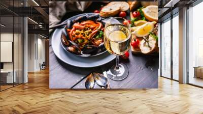 A glass of dry white wine on the background of Italian cuisine. Pasta, mussels and wine. Wall mural