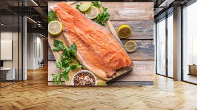 Close-up fresh appetizing salmon steak. Spices, lemon, fresh parsley and ice. Rustic background. Organic food. Top view Wall mural