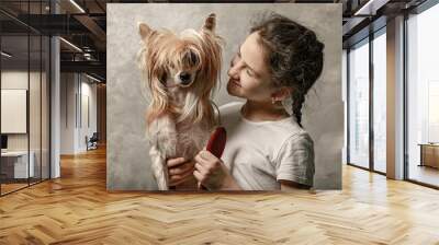 Cute smiling caucasian teenage girl with her little dog on a gray background. Portrait with your favorite pet. Grooming and taking care of your beloved dog. Wall mural