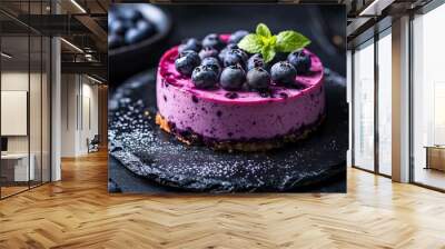 A vegan blueberry cheesecake set against a dark, black background, featuring the raw cake topped with fresh blueberries and other berries, highlighting its rich texture and vibrant color. Wall mural