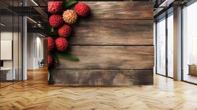 Fresh lychee fruits are beautifully arranged on a rustic wooden background, showcasing their unique, bumpy red skin and green leaves.  Wall mural