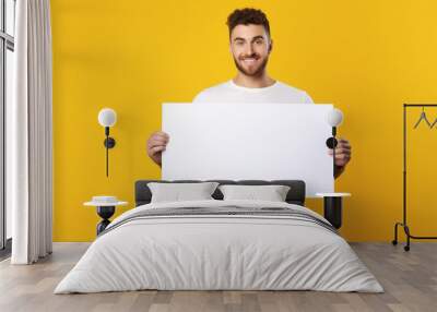 a handsome man holding a blank placard sign poster paper in his hands Wall mural