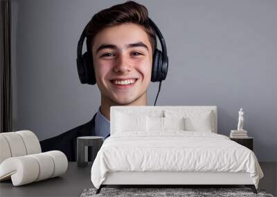 A smiling young man with headphones on a grey background Wall mural