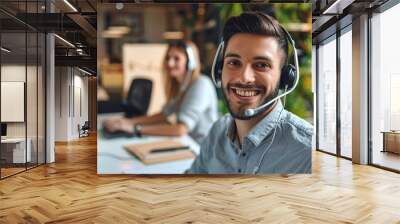 Smiling man call center operator with headset and female agent working in the background at office Wall mural